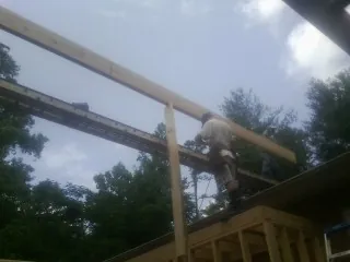 Carpenter setting a ridge beam over a new addition frame — Ice Dam Removal by Roofing Brothers in Granite
