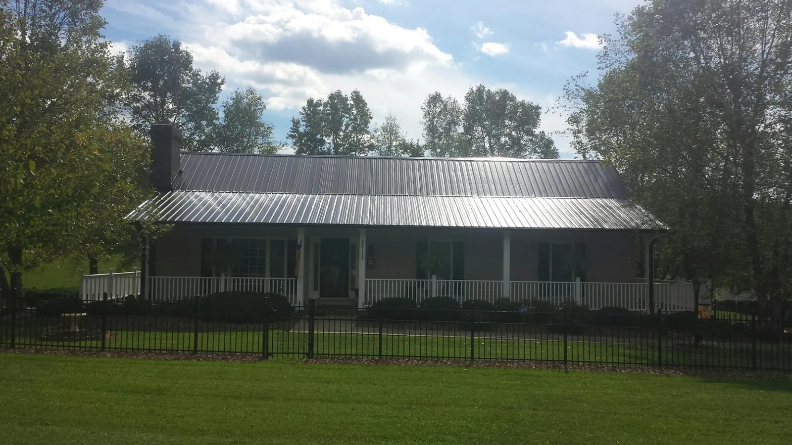 Gray metal roof on a brick ranch with a full width front porch — Gutter Guard Installation work by our crew in Granite